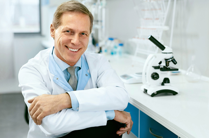 Durch Politik und Verwaltung gibt es eine ständig steigende Regulierung und Reglementierung der Ärztlichen Versorgung. Wer soll da noch den Überblick behalten? Das betrifft auch die Vorsorge. Nur mit einer sicheren Abstrichmethode können Sie Ihre Patientinnen wirklich über deren Gesundheitsstand informieren und Übertherapien vermeiden. Freundlicher Frauenarzt im Kittel sitzt vor Labortisch mit Mikroskop, die Arme übereinandergeschlagen und schaut selbtbewusst lächelnd, von sich und seiner Arbeit überzeugt.