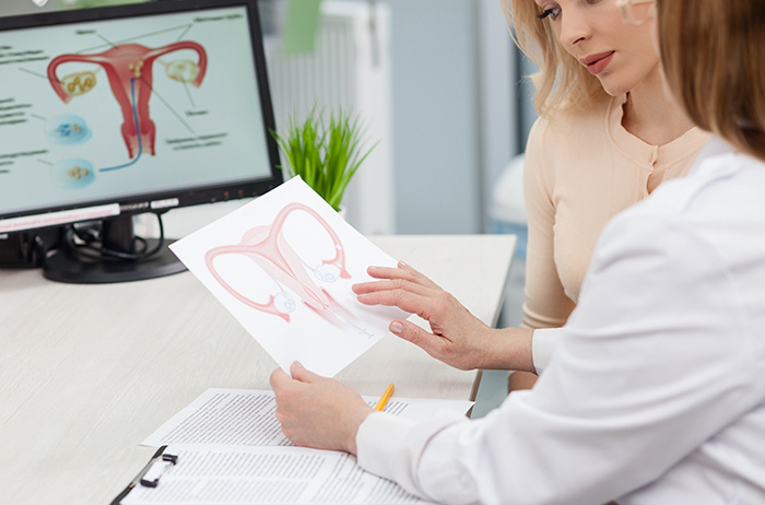 Ärztin und Patientin schauen gemeinsam auf ein Bild vom Gebärmutterhals bei der Vorsorgeuntersuchung.